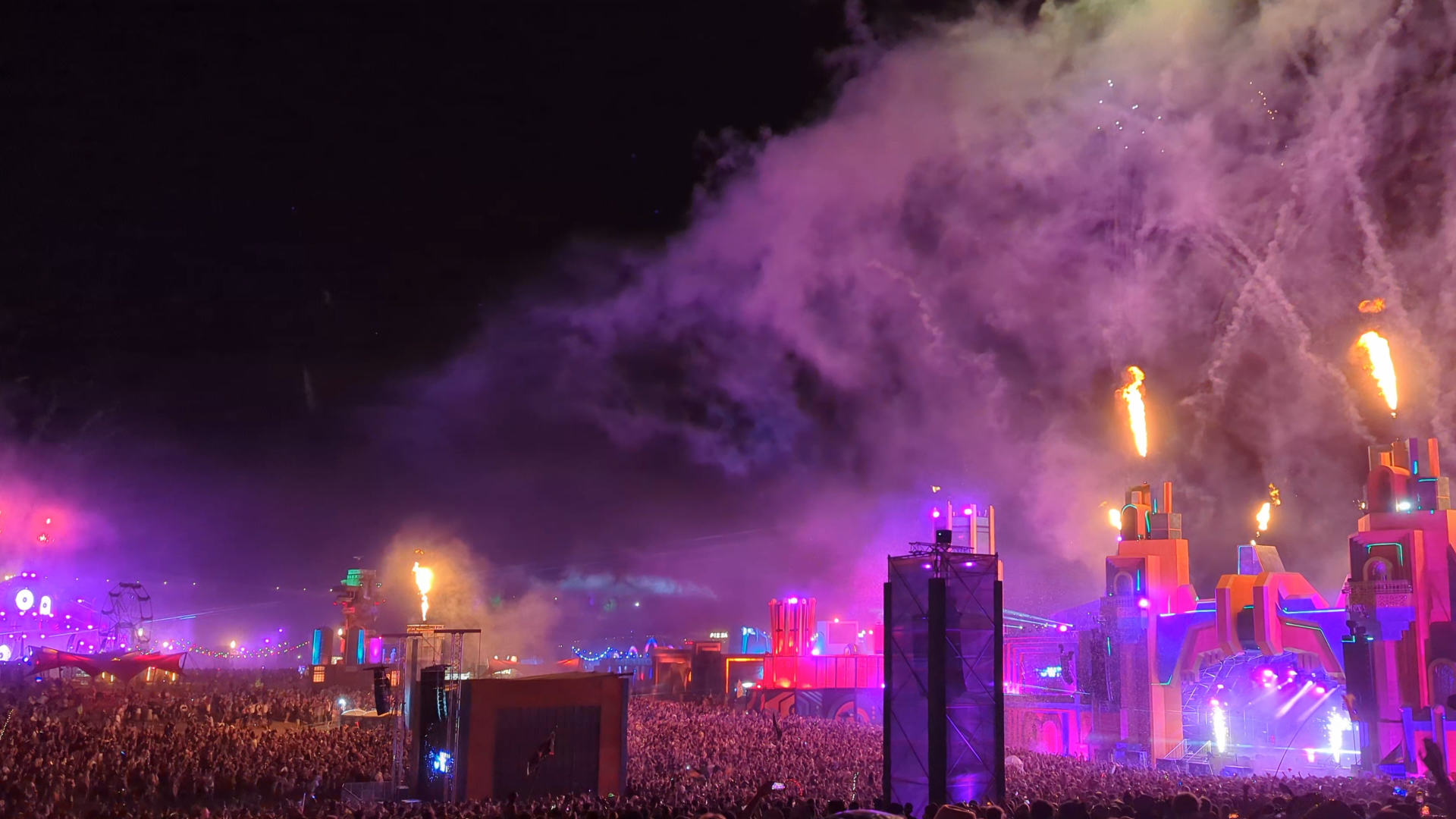 Festival stage at night — fire columns and purple light over a massive crowd — a Play Pause Films production